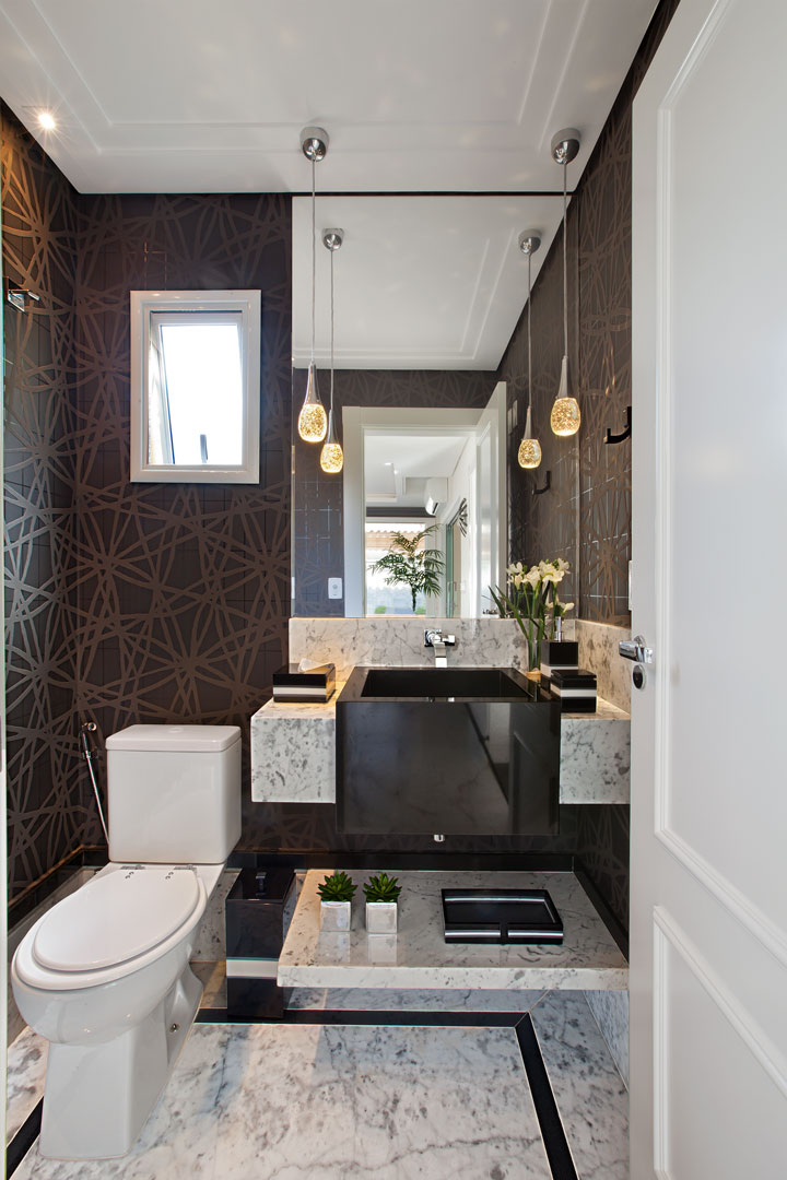 O lavabo apresenta o contraste do papel de parede escuro (Griffe A) com o piso e a bancada em mármore Carrara. As louças e metais são da Ornamentare