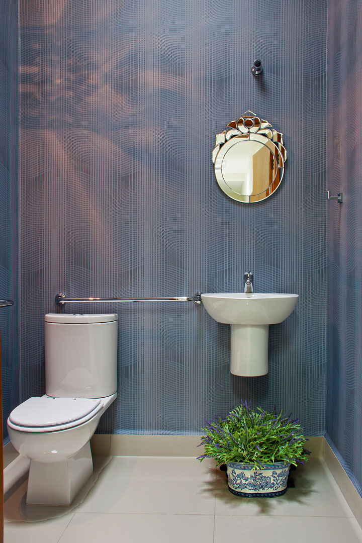 A acessibilidade foi o destaque do lavabo. O uso do papel de parede azul e do espelho bisotê traz contemporaneidade ao ambiente