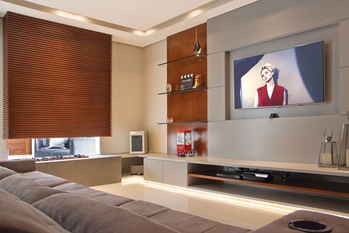O Home Theater traz móvel em laca cinza e madeira natural (Marcenaria Gobato), que faz a junção com o painel de TV.