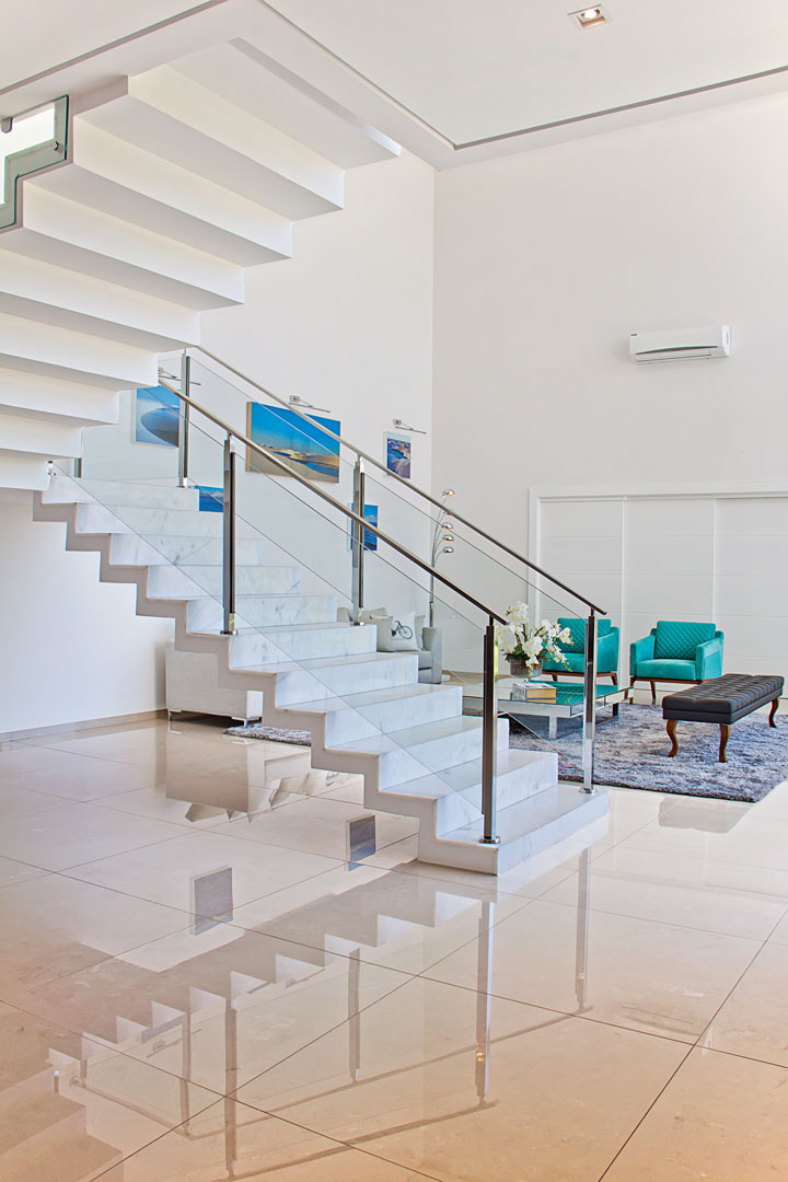 O living exibe a beleza da escada escultural executada com degraus de mármore branco. Sofá, quadros e acessórios da Secol Home Center
