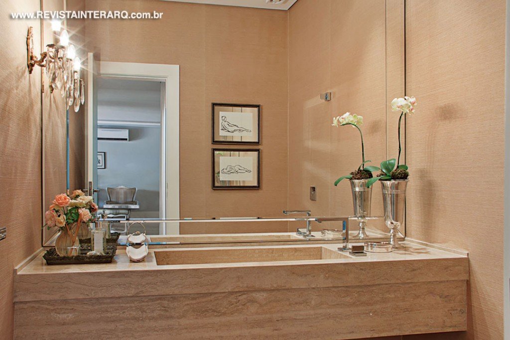 O lavabo com bancada em mármore Travertino Romano e espelho bisotê 