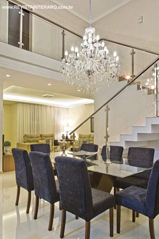 O pé-direito duplo na sala de jantar revela a escada e os grandes vãos concebidos para favorecer a luminosidade e o conforto térmico