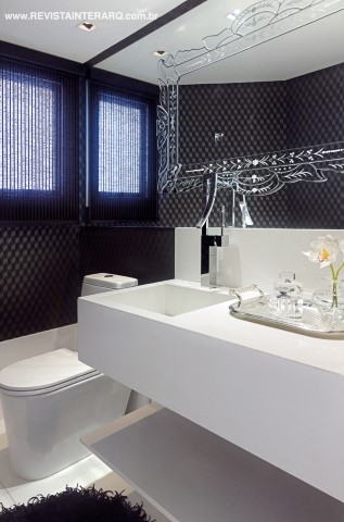 O lavabo brinca com o jogo “claro e escuro”, com o piso em mármore Branco Piguês e bancada em Nanoglass branco ressaltados pela parede com papel de parede gráfico. Destaque para o espelho veneziano colocado sobre a parede espelhada