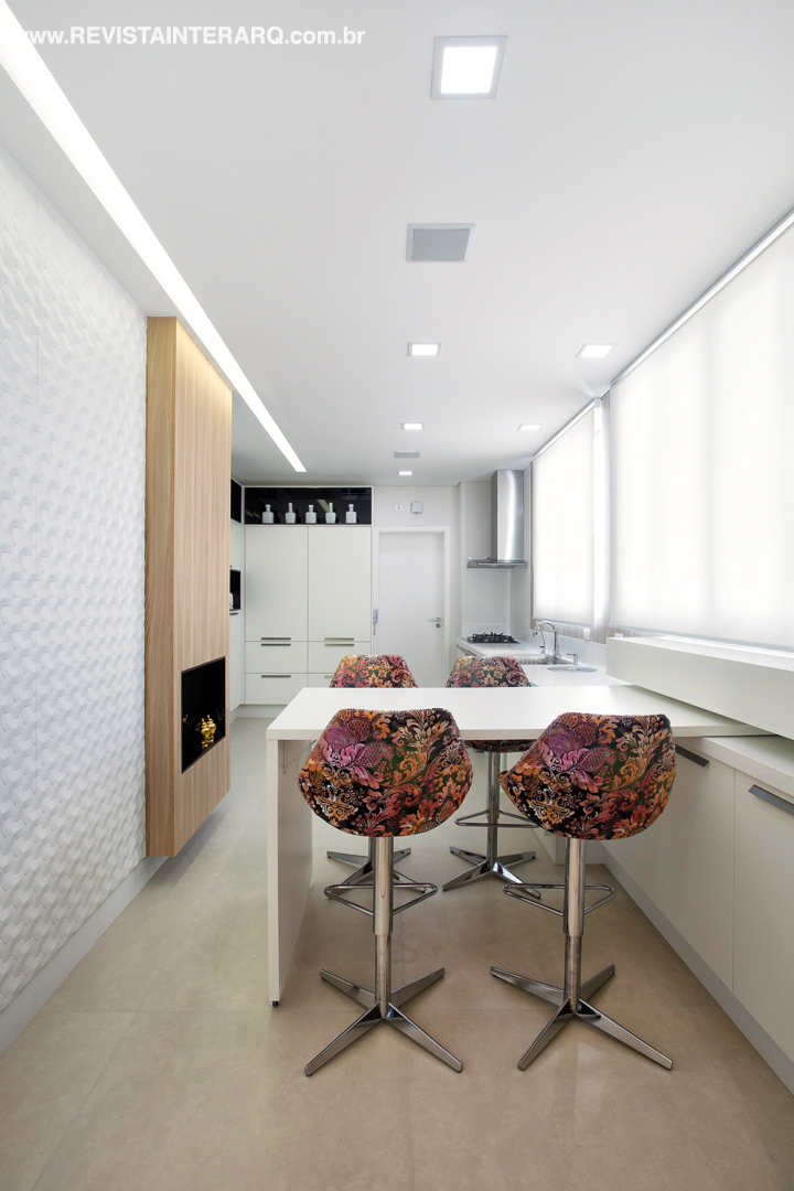A parede com revestimento texturizado branco e o volume amadeirado dão movimento à cozinha