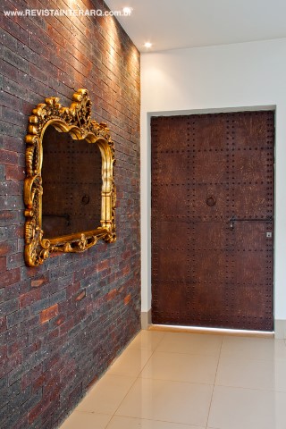 O hall interno ganhou tijolos estilo inglês e luzes pontuais direcionadas para o espelho com moldura dourada