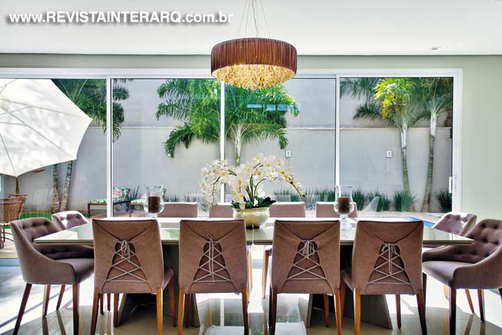A elegante composição com cadeiras estofadas, mesa de vidro e lustre de tecido e cristais forma o jantar