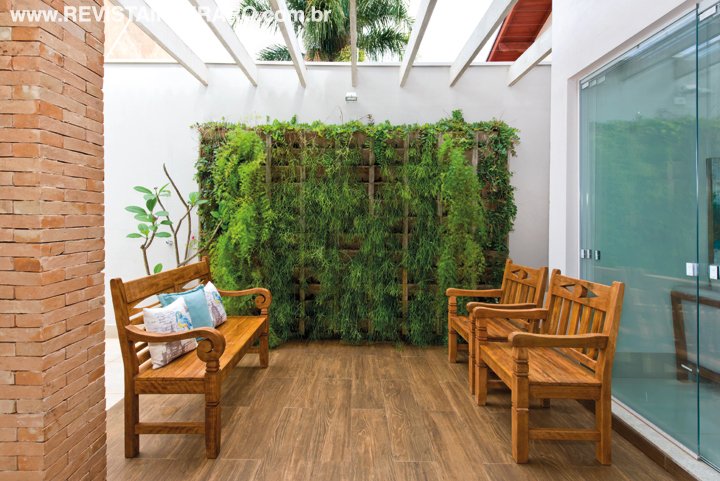 Com piso em porcelanato amadeirado e jardim vertical da Ecobloco. Móveis de madeira de demolição da Espaço Moderno