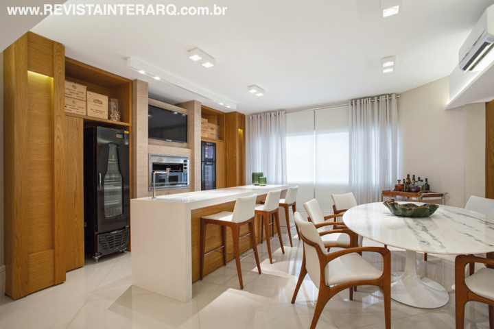 Na área gourmet, a mesma paleta aparece na forma de Silestone na bancada e mármore Travertino Romano na churrasqueira. TVs e eletros da Digital Home