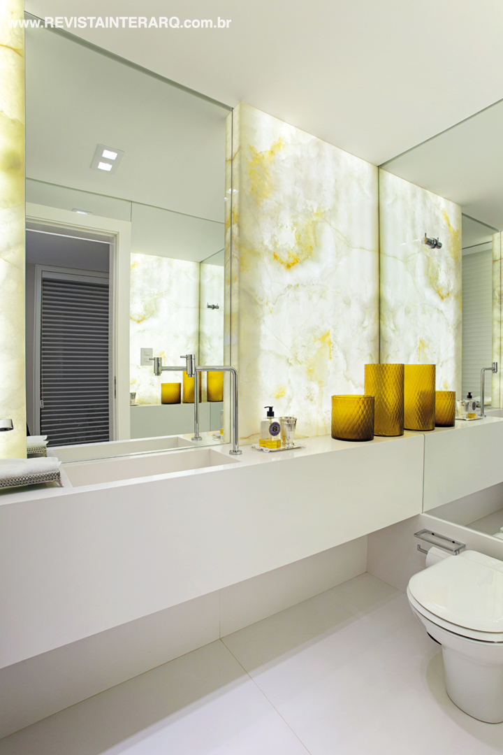 No lavabo, o painel de ônix iluminado é o luxuoso elemento surpresa. Toda a marcenaria personalizada foi executada pela Móveis RM