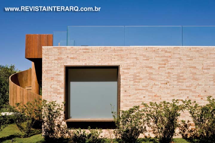 O acabamento em tijolinho e o uso da madeira nos pergolados confere um ar receptivo à fachada do pavilhão. A escada externa leva ao terraço aberto