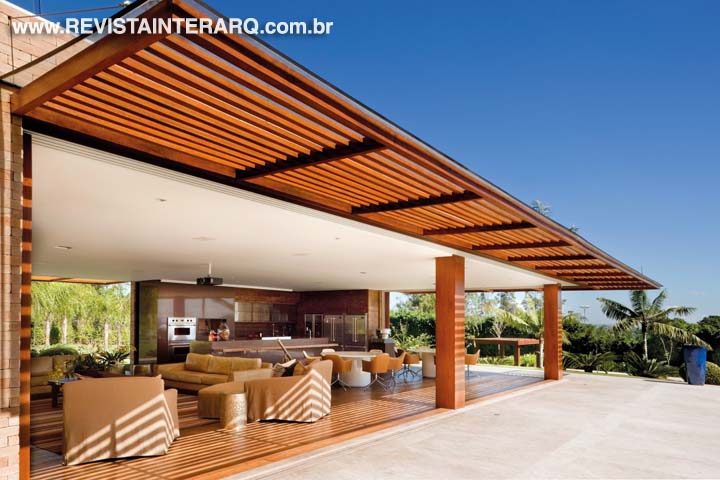 A pérgola em madeira com cobertura em vidro minimiza o sol nos espaços internos. As amplas aberturas proporcionam mais frescor com a ventilação cruzada