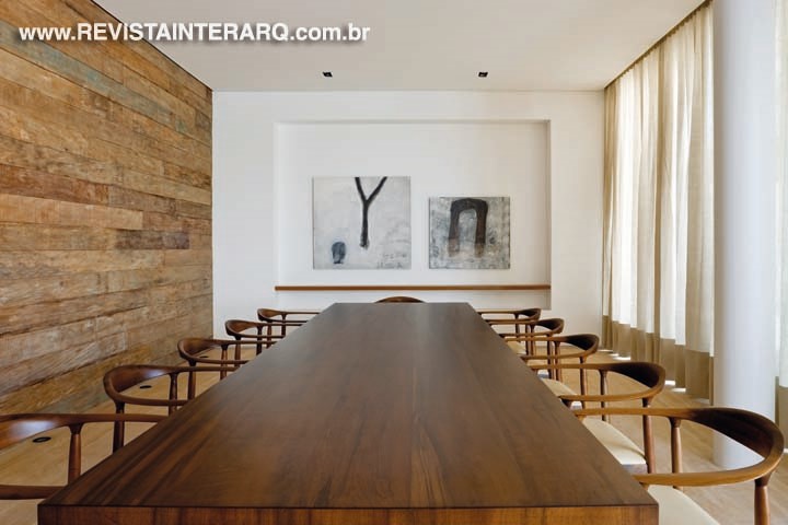 Mesa de jantar em madeira, cadeiras The Chair, de Hans Wegner (Hill House), e telas do artista plástico Marco Túlio Rezende