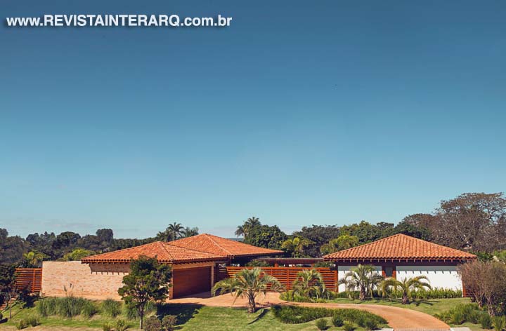 Vista mais do alto, a fachada revela nitidamente os três volumes distintos da residência. O uso da madeira cumaru como estrutura da casa, aliado ao telhado aparente com lambris e aos tijolinhos aparentes, trouxe o aconchego que a família buscava. O paisagismo é de Ana Paula Roseo