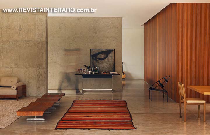 O tapete listrado vibrante Kilim faz contraponto com piso em concreto e com o mobiliário 