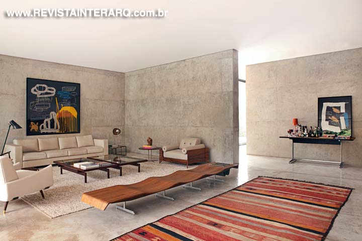 O tapete listrado vibrante Kilim faz contraponto com piso em concreto e com o mobiliário clean