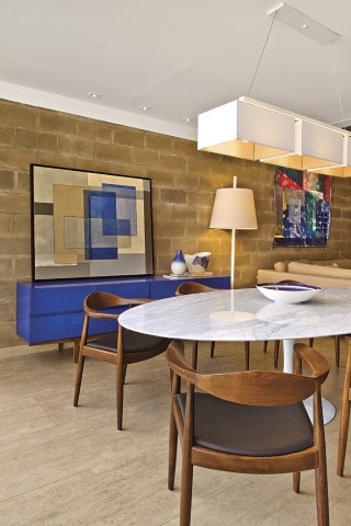 O buffet em laca azul e a tela no mesmo tom dão o toque arrojado ao jantar com móveis de design, como a mesa Eero Saarinen e luminárias brancas de piso e teto