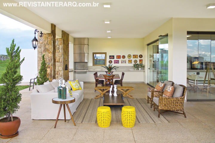 A varanda tem o despojamento dos garden seats amarelos, poltronas de fibra e sofá branco (tudo da Aimar Móveis). Quadros da Arte Própria