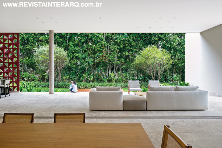 O espaço gourmet e a exuberante cerca-viva de Ficus emoldurada pelos elementos arquitetônicos. Sobre o piso em mármore Bege Bahia (Multipedras), o décor é minimalista, com poucos móveis de estilo