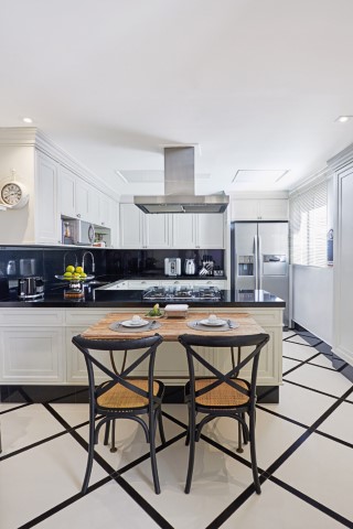 A cozinha com móveis planejados brancos, bancada em granito preto e piso em porcelanato (Casa dos Construtores) 
