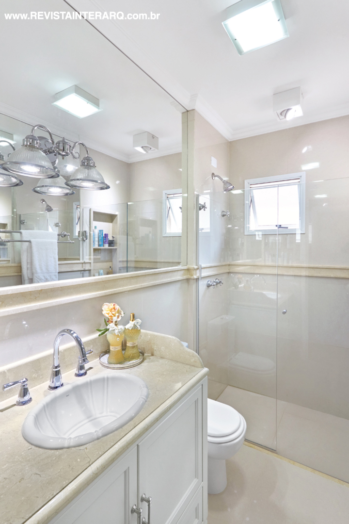 A delicadeza com acabamentos claros (Casa dos Construtores) acentuam a amplitude visual do banho, com box e espelhos da Vidraçaria Rio Preto