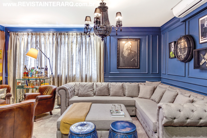 No living, as paredes azuis causam impacto visual e emolduram o sofá em “L” (Estofados Cardoso). Os garden seats e o lustre são da Marizza Prado. Tapete da By Kamy