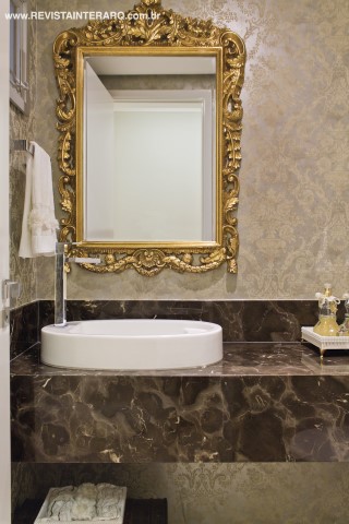 O clássico espelho dourado (DKasa Interiores) do lavabo acompanha a linguagem do papel de parede. A bancada é em mármore, da Vidraçaria e Marmoraria Destak. Louças e metais da Casa dos Construtores