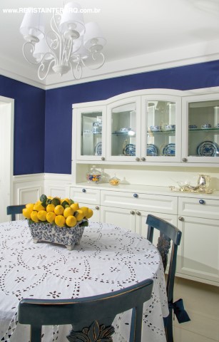 O contraste do azul e branco e as boiseries em meia parede conferiram charme à sala de almoço com parede e cadeiras azuis. Louceiro em laca branca da Florense