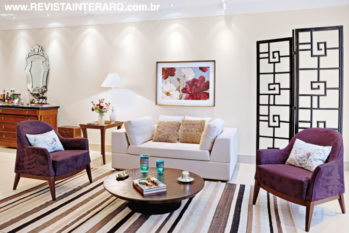 O tapete listrado e as poltronas roxas (UneRobusti) dão o ar moderno ao living. A composição conta ainda com mesas da Robusti