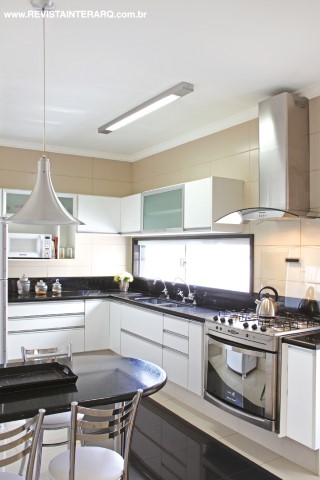 O perfil moderno da cozinha, está expresso nos armários e na iluminação pontual. Bancada em granito preto da Marmoraria Exclusive