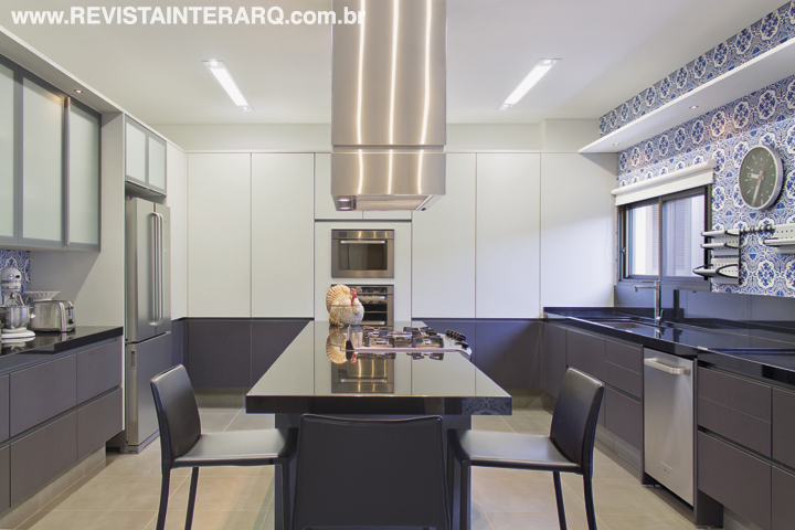 A cozinha contemporânea em dois tons, com projeto executado pela Kitchens, ganhou bossa com o papel de parede com estampa de Christian Lacroix. As bancadas são em granito Preto Absoluto. Coifa da Refrigeração Araçatuba e banquetas em couro da Perfil Casa