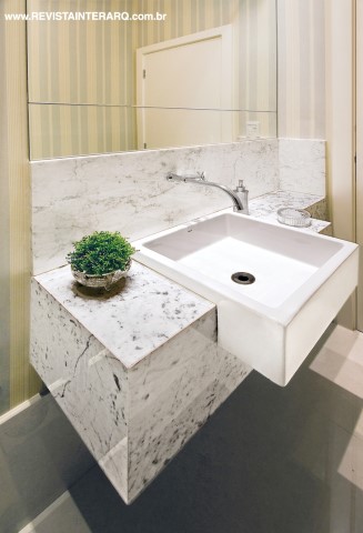 O lavabo, ganhou um visual elegante com bancada em mármore Carrara, painel de espelhos bisotados e cuba com linhas retas (Duo). As paredes são revestidas com papel de parede listrado