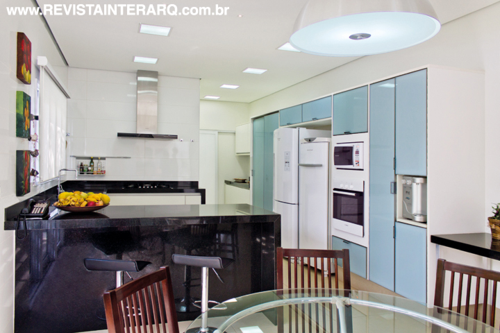 Na cozinha, armários com vidro branco (Favorita) fazem contraponto à bancada em granito Preto Absoluto (Rolsilva Marmoraria)
