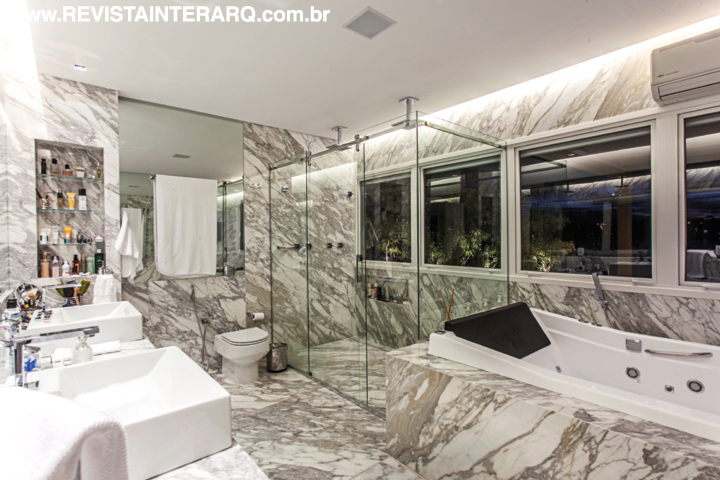O mármore Calacata Gold (Marmoraria Alvorada) recobre as paredes e piso da sala de banho. A beleza da pedra é ressaltada pela iluminação embutida (Dessine) junto à parede 