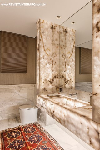 No lavabo, a bancada em ônix mármore translúcido (Marmoraria Alvorada), com iluminação embutida (Dessine), encanta o olha