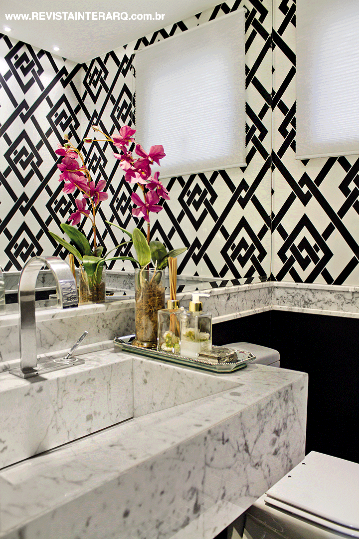 O papel de parede geométrico (Artenal) é o charme do lavabo com bancada e faixa em mármore Carrara. A persiana é da Griffe A e acessórios da Krieê Decorações