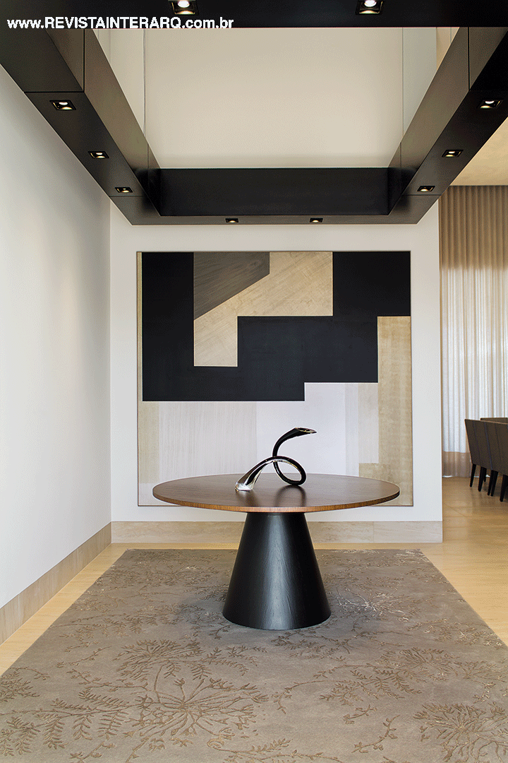 A composição do hall de entrada brinca com as formas geométricas na mesa, quadro e teto