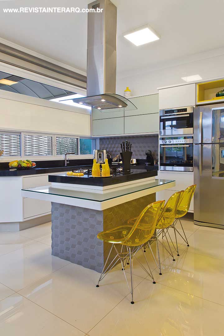 Na cozinha, os armários planejados (Vinter Móveis) revelam pitadas de amarelo, mesma cor dos acessórios (Casa de Cora) e das cadeiras (Galeria Top Kazza | Saccaro). Bancada em granito preto da MG Marmoraria